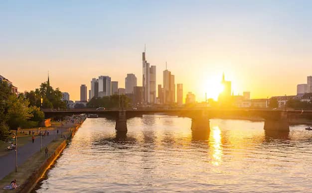 Frankfurt downtown skyline of glass skyscrapers glowing at sunset above the Main river