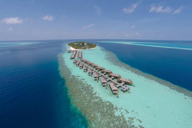 Aerial view of a Maldives resort island with overwater villas