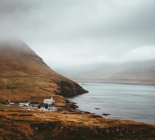 A small Faroese village of coloured houses on a narrow strip of green land between the grey North Atlantic and steep dark mountains