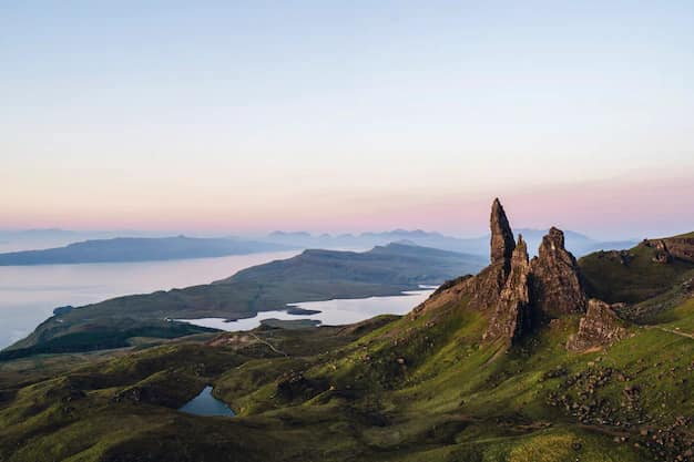 The Old Man of Storr, a tall basalt pinnacle on the Trotternish peninsula of the Isle of Skye, rising above grassy slopes under a shifting Highland sky