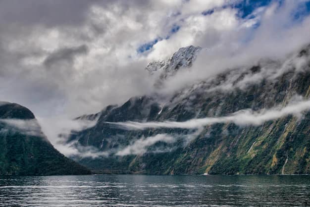 Milford Sound fiord in New Zealand with sunlit peaks reflected in still water