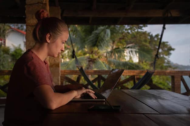 Woman in a straw hat working on a laptop at a stylish tropical cafe while travelling
